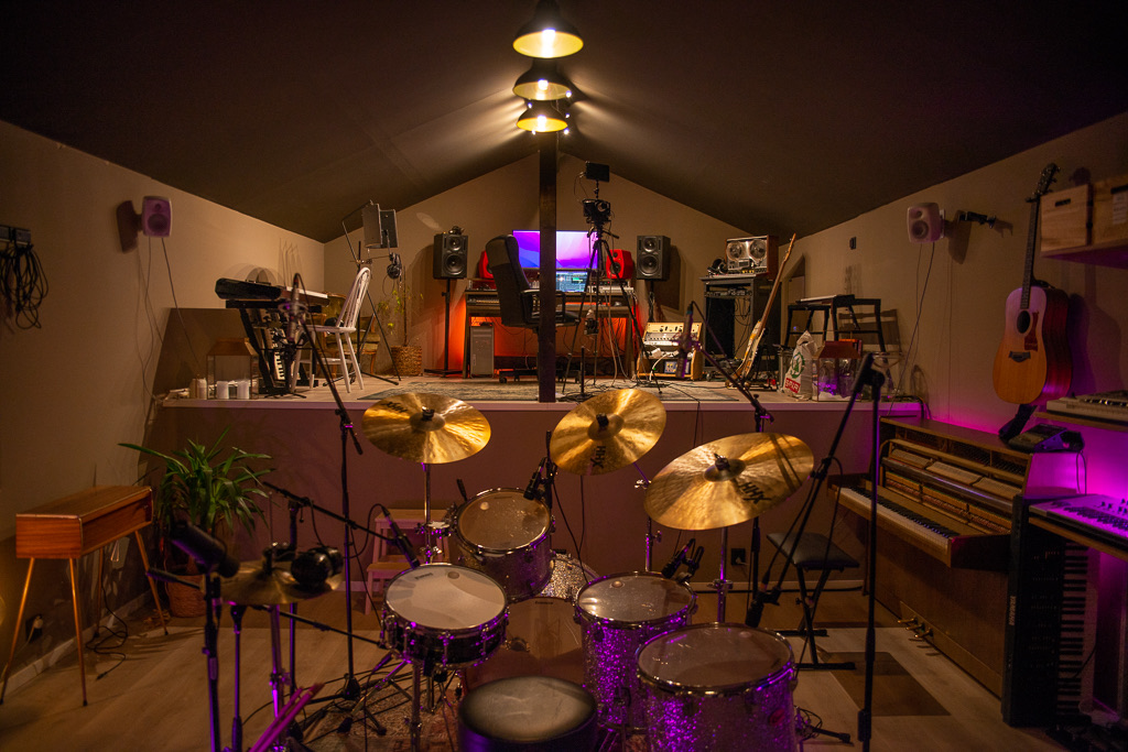 Studiorommet i Bortevekk Studio med trommesett, keyboards og varmt lys